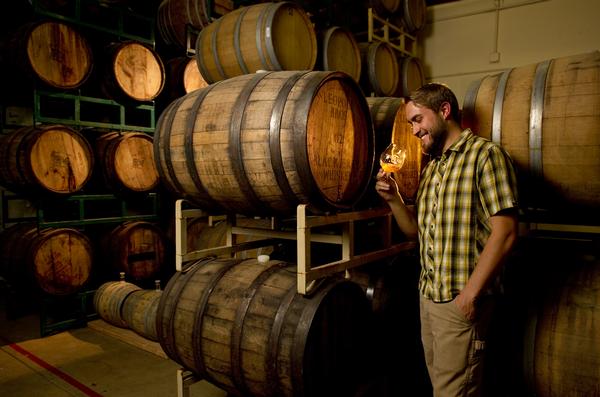Life is good when your work is beer.... as  demonstrated by Chad Yakobson owner/brewer of Crooked Stave Artisan Beer Project with his barrels of beer on Wednesday, September 12, 2012 at his NW Denver headquarters and tasting room.  He was holding a golden sour beer that is still aging in the former whiskey barrels. The Barrel Cellar tasting room has just opened at the 1441 W. 46th Ave, Unit 19 location.  Cyrus McCrimmon, The Denver Post